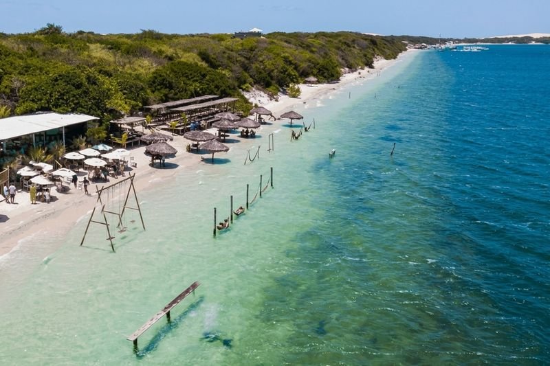 Praia de Jericoacoara com águas claras e coberturas de palha na orla